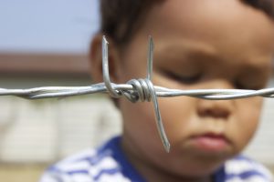 Sad Asian Boy Behind Barbed Wire